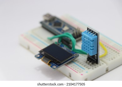 DHT11 or Temperature and humidity sensor with OLED display circuit on a breadboard run by some microcontroller on the background