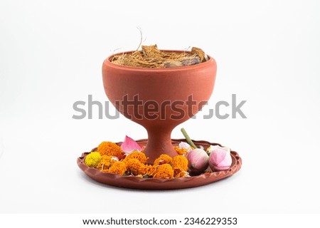 DHUNUCHI WITH COLOURFUL FLOWER ON CLAY THALI . ISOLATED ON WHITE WITH SELECTIVE FOCUS.