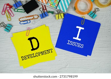 DI - Development Issues text on stick note with stationery on concrete background