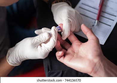 Diabetes check up.Medical assistant using finger prick for glucose sugar measuring level blood test.Close up shot with selective focus.