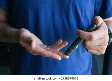 Diabetes concept. Male hands using lancet on finger at home to check blood sugar level, glucometer, 