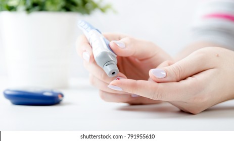 Diabetes Doing Blood Glucose Measurement. Woman Using Lancet And Glucometer.