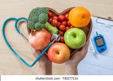 Diabetes monitor, Cholesterol diet and healthy food eating nutrition, World diabetes day concept with clean fruits in nutritionist's heart dish and patient's blood sugar control, diabetic measurement