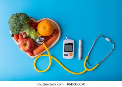 Diabetes Monitor, Diabetic Measurement. World Diabetes Day Concept With Clean Fruits In Nutritionist's Heart Dish.
Healthy Food Or Clean Food Concept.