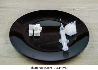 Diabetic Coma: A Few Cubes Of Sugar And Syringe With Needle For Injection, Cotton Wool, On The Contrary, On The Black Plate On The Table