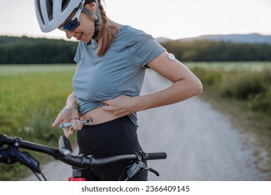 Diabetic cyclist injecting insulin in her belly during bike tour. - Powered by Shutterstock