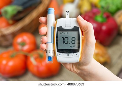 Diabetic Diet And Healthy Eating Concept. Glucometer And Vegetables In Background.