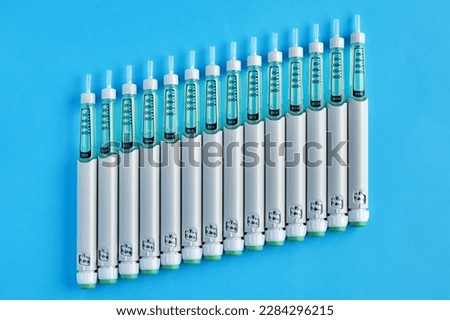 Diabetic insulin pens lined up as a rising graph on a blue background. Rise in the cost of medicines. Increase in insulin requirement
