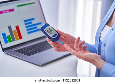 Diabetic Patient Checks Blood Glucose Level Using Glucometer. Diabetes Control And Studying Glucose Graphs On A Computer Online At Home 