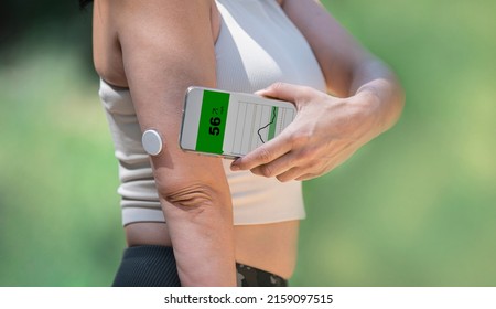 Diabetic woman monitoring and checking glucose level with a remote sensor and a new technology with an app in smartphone