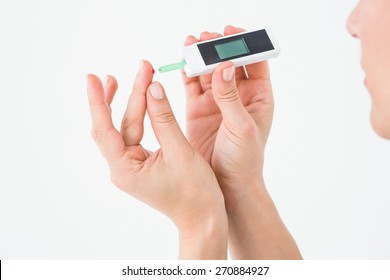 Diabetic Woman Using Blood Glucose Monitor On White Background