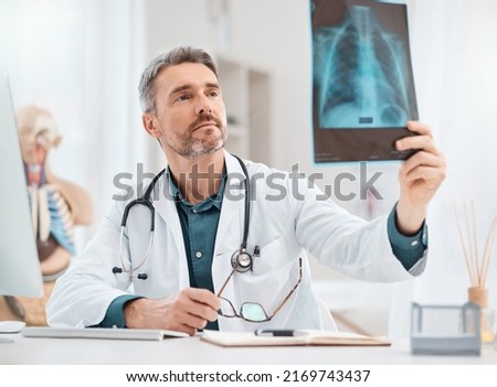 Diagnosing and treating the injury. Shot of a mature doctor analysing x-ray scans in a medical office.