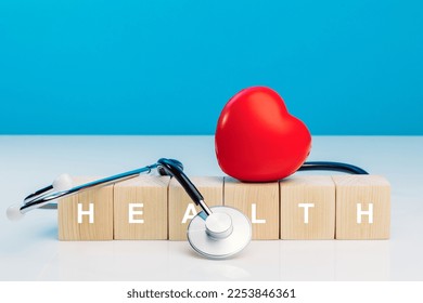 Diagnosis cardiologist concept. Text health on wooden cube blocks with red heart and stethoscope on blue background. Equipment check heartbeat and pulse of patient