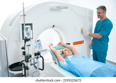 Diagnostic Man And Woman In CT Scan Room In Medical Facility