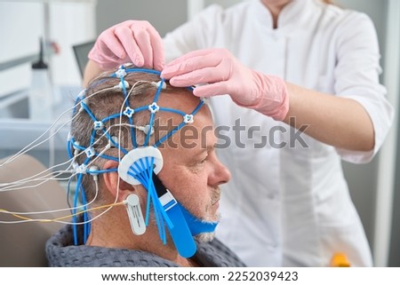 Diagnostician doctor attaches electrodes to the patient head