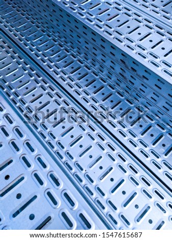 Diagonal arrays of holes and slits in galvanized perforated cable trays - abstract image. Metal digital infrastructure concept. Close up image.