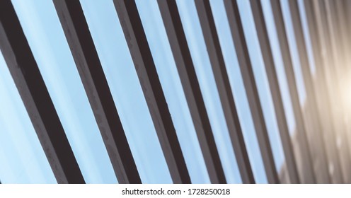 Diagonal Black Shutters Planks Against Clear Blue Sky And Bright White Sunlight Reflection Extreme Close Low Angle Shot