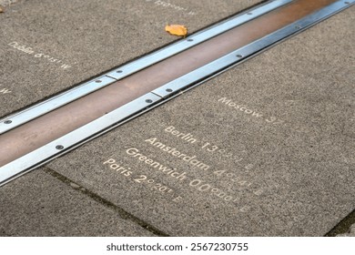 Diagonal composition showing the Prime Meridian at Greenwich, London, with longitude markers engraved on the ground, representing global time zones.