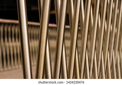 Diagonal Crossed Brushed Aluminum Metal Bars With A Slight Golden Hue Receding Into The Distance On A Small Modern Bridge, Shiny & Reflective