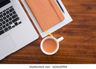 Diagonal Layflat Of Workspace. Self Starter, Meeting Minutes, Note Taking And Working As A Student Or At A Cafe/ Coffee Shop On Wooden Table With Cup Of Coffee/tea. Mobile Office, Work Anywhere