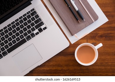 Diagonal Layflat Of Workspace. Self Starter, Meeting Minutes, Note Taking And Working As A Student Or At A Cafe/ Coffee Shop On Wooden Table With Cup Of Coffee/tea. Mobile Office, Work Anywhere