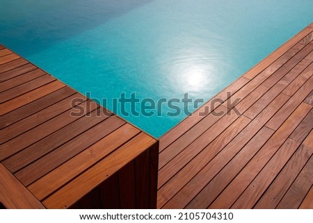 Diagonal lines of wood in detail decking and blue water swimming pool abstract background