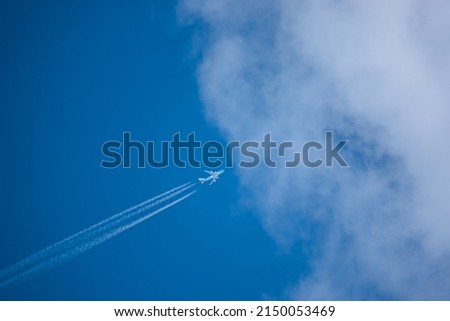 diagonal lower left to upper right high altitude contrails from a four engine KLM Boeing 747-400 Cargo Jumbo jet aircraft entering cloud blue sky