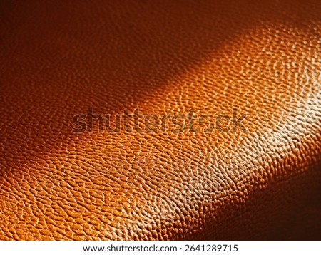Diagonal ray of light falling on orange leather surface