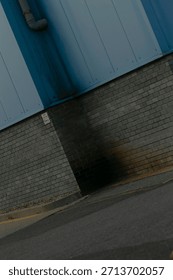 diagonal slice of blue panel over brick creating abstract geometry, angled perspective suggesting dynamic frame, drone operator role implied capturing unusual viewpoint, modern minimalist urban study