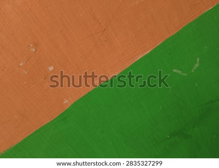Diagonal split two tone painted concrete wall surface. Bright green and orange colors intersecting on weathered wall texture.