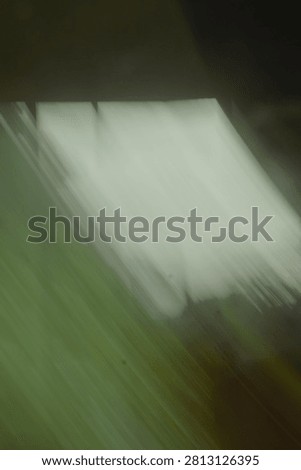Diagonal streaks of light and shadow create an abstract composition with a dominant green tone, suggesting motion