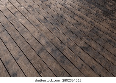 Diagonal view of weathered deck boards with grooves and stains