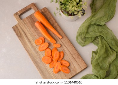 Diagonally Cut Fresh Carrots On A Cutting Board Against A Neutral Background