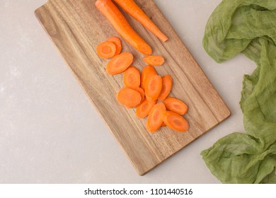 Diagonally Cut Fresh Carrots On A Cutting Board Against A Neutral Background