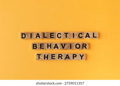 Dialectical Behavior Therapy: words composed of small wooden blocks - vibrant yellow background.