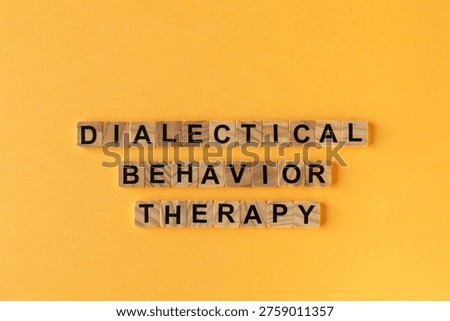 Dialectical Behavior Therapy: words composed of small wooden blocks - vibrant yellow background.