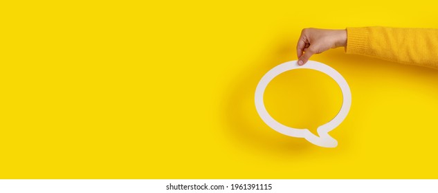 Dialogue bubble in hand over yellow background, panoramic image - Shutterstock ID 1961391115