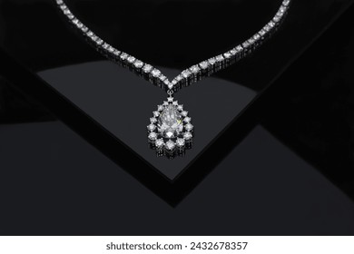 Diamond necklace with large yellow pear cut diamond on black background.