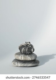 a diamond ring balancing on some pebbles on a white empty background