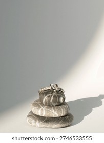 a diamond ring balancing on some pebbles on a white empty background