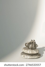 a diamond ring balancing on some pebbles on a white empty background