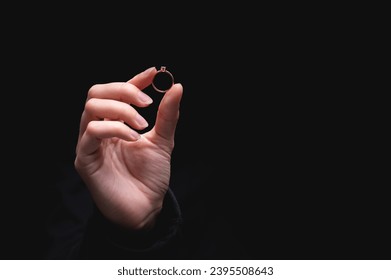 Diamond ring in a girls hand on a black background. Concept of love and wedding or divorce and unsuccessful marriage - Powered by Shutterstock