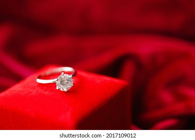 Diamond Ring With Jewelry Gift Box On Red Fabric Background