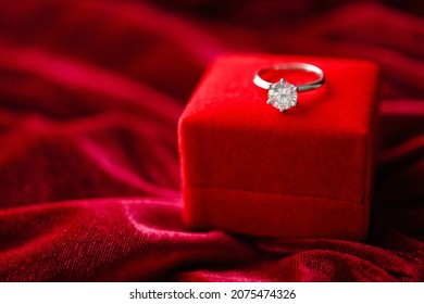 Diamond Ring With Jewelry Gift Box On Red Fabric Background