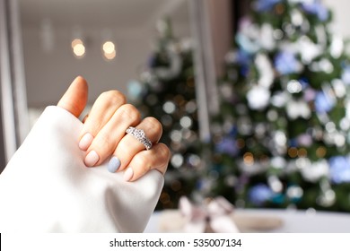 Diamond Ring On A Finger Under The Christmas Tree. Holidays And Celebrations Concept.