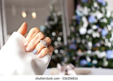 Diamond Ring On A Finger Under The Christmas Tree. Holidays And Celebrations Concept.