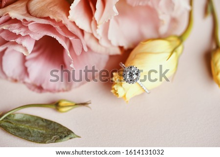 Diamond Ring and Pink Flower Background. Close up of an elegant engagement diamond ring. 