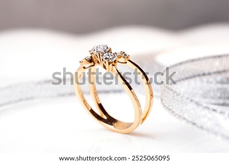 diamond ring with three round diamonds, set in a rose gold band that twists and curves around the finger. The ring is displayed on a white marble surface, with soft, natural light illuminating it