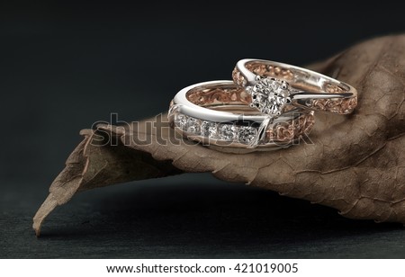 Diamond rings, overlapping male and female, set on leaf harmonizing the ring design and color.