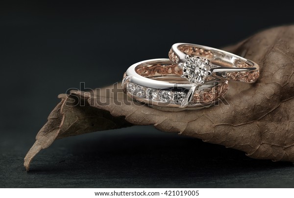 Diamond rings, overlapping male\
and female, set on leaf harmonizing the ring design and\
color.